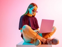 Modern Girl with laptop, tablet computer. Free creativity. A young blogger makes a Home office. Colored Neon light and background.